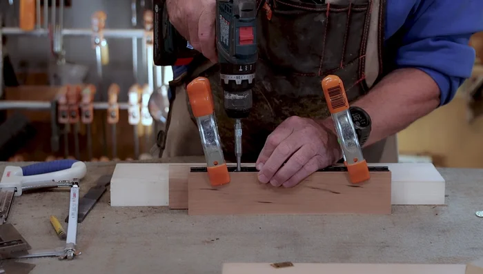 Use a centering bit (5/64" or smaller for smaller hinges) to pre-drill pilot holes for the screws. Ensure the bit is centered and flush against the wood to guarantee accurate screw placement.