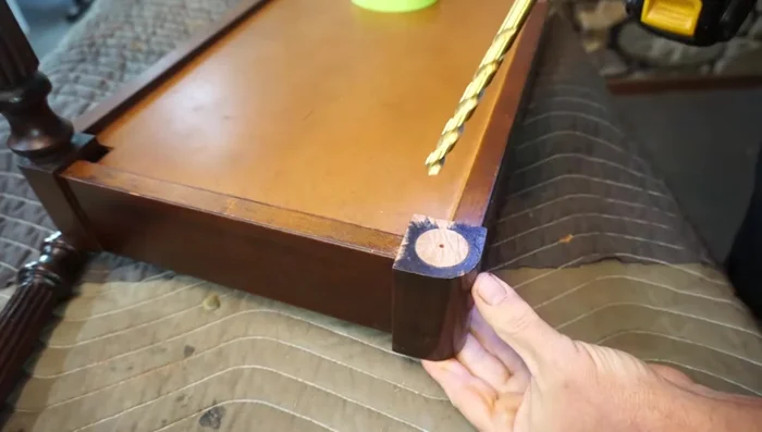 Enlarge the 1/8 inch pilot hole to 3/8 inch using a 3/8 inch drill bit, ensuring it extends beyond the break on both the leg and the bench base.