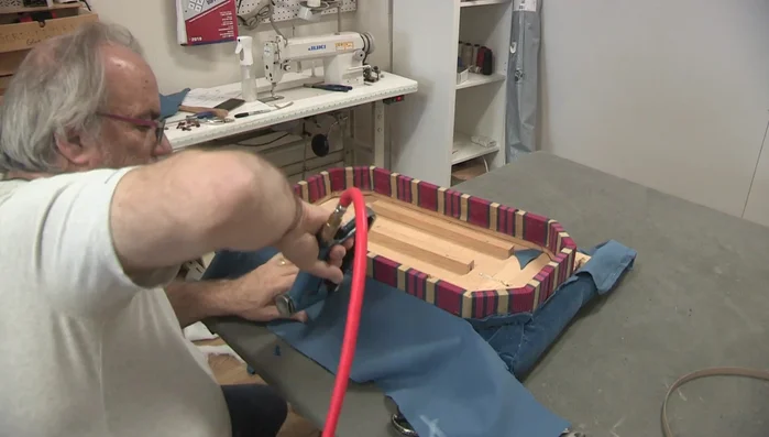 Blind tack the edges. Secure the fabric along the edges using blind tacking and cardboard tacking tape for a clean finish.