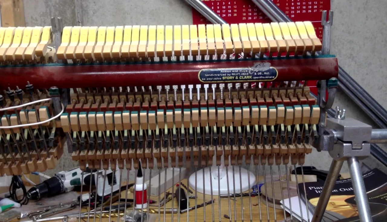 Close-up view of the spinet piano action components laid out on a workbench.
