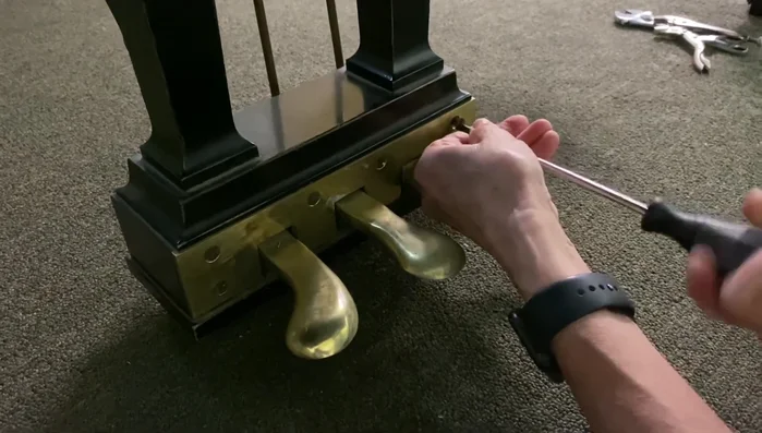 Remove the plate screws at the front of the piano, keeping them in order.