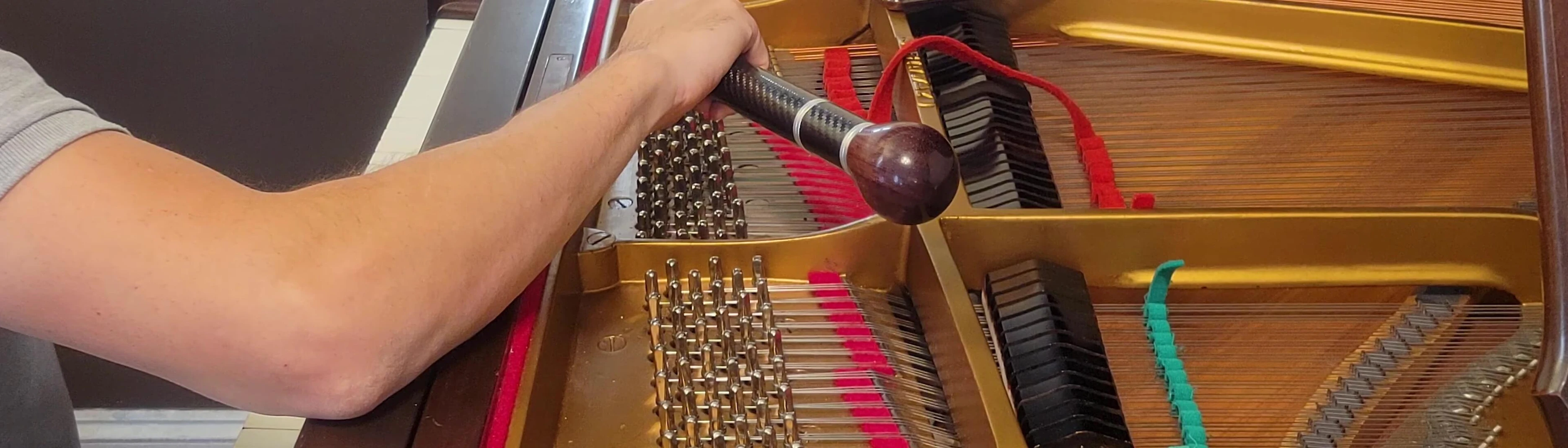 Technician adjusting a piano string with a tuning hammer